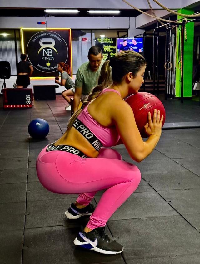 Entrenador acompañando ejercicio con balón medicinal